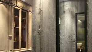 A modern interior with a wooden accent wall, a glass door leading to a room, and a fur-covered bench. - Hidden Hotel (Paris)