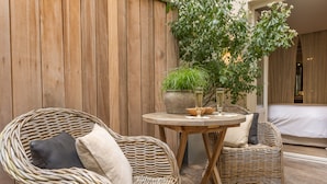 A wicker lounge area with two chairs, a round table, and a potted plant. - Hidden Hotel (Paris)