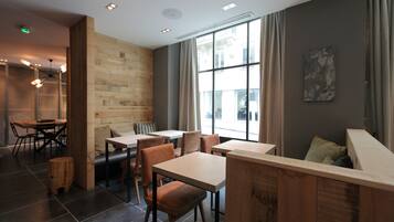 A modern cafe with wooden furniture, large windows, and a stone wall.