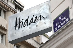 A hotel sign with the name "Hidden" and a street sign "Rue de l'Arc de Triomphe".