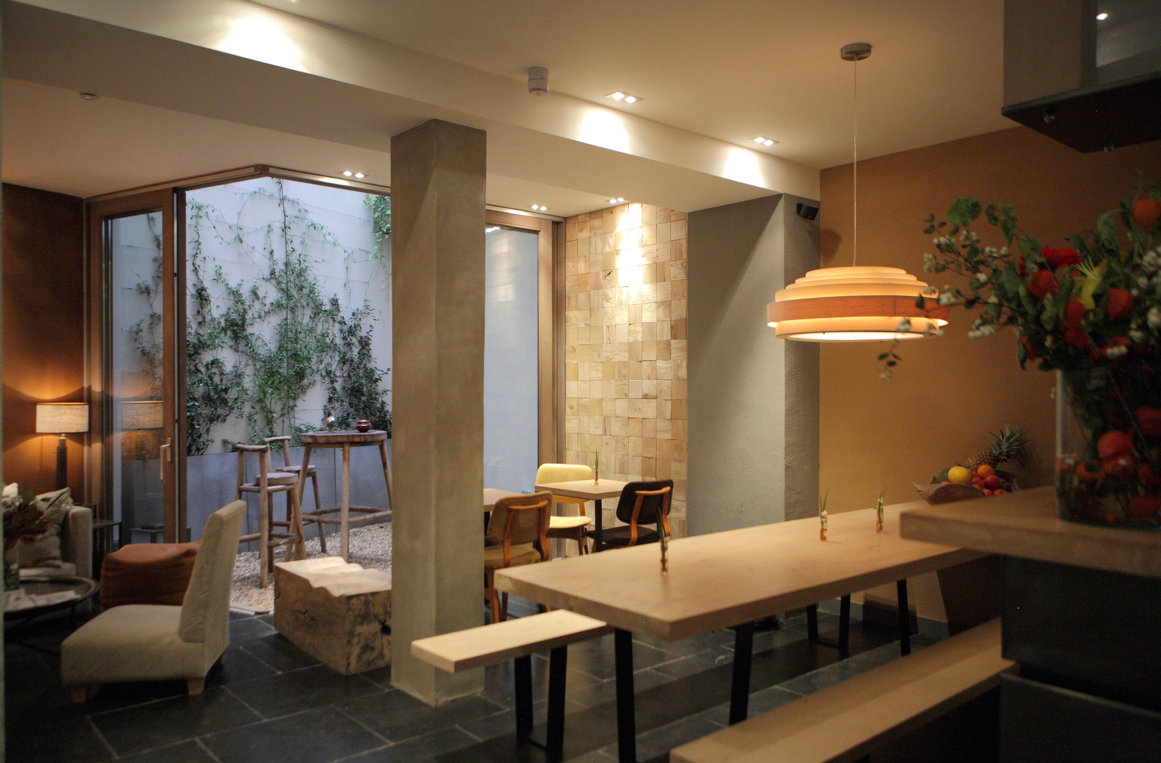 Un comedor moderno con una mesa larga, bancos y sillas. Se ve una ventana grande con vistas a la vegetación exterior.