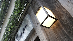 A wooden wall with a sign that reads "Hidden" and two wall-mounted lights. - Hidden Hotel (Paris)