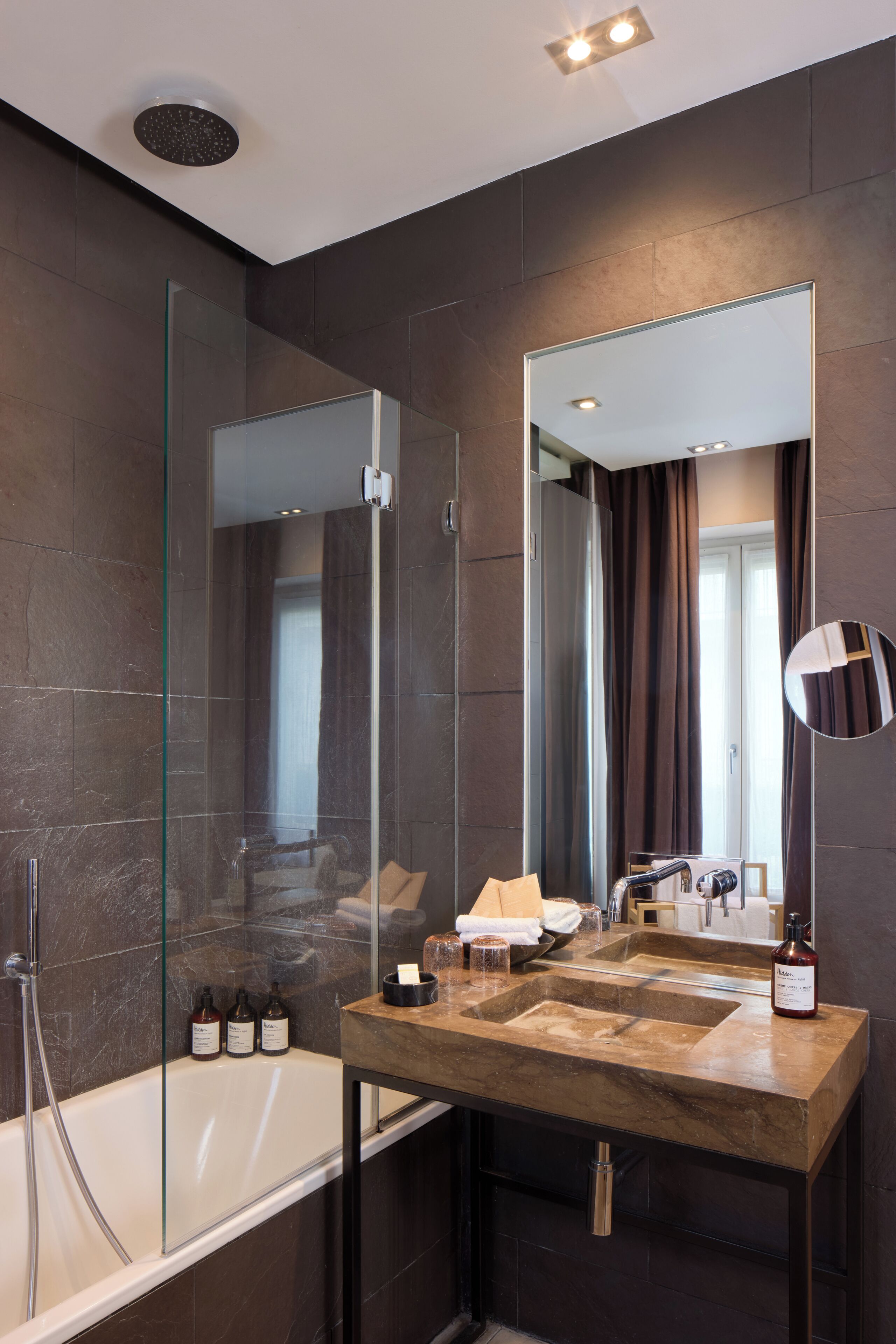 A modern bathroom with a glass-enclosed shower, a large mirror, and a marble sink.