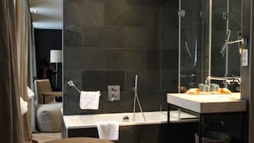 Un baño moderno con bañera, un espejo grande y una mesa redonda.
