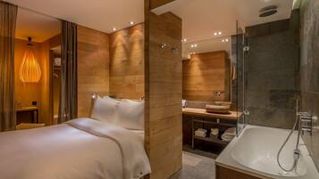 Una habitación de hotel moderna con una cama grande, una ducha con cerramiento de vidrio y un diseño de pared de madera.