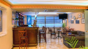 A spacious living area with a bar, seating, and a large window. - Nicola Hotel (Athens)