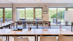 Een vergaderruimte met een lange tafel, stoelen, waterflessen en een whiteboard.