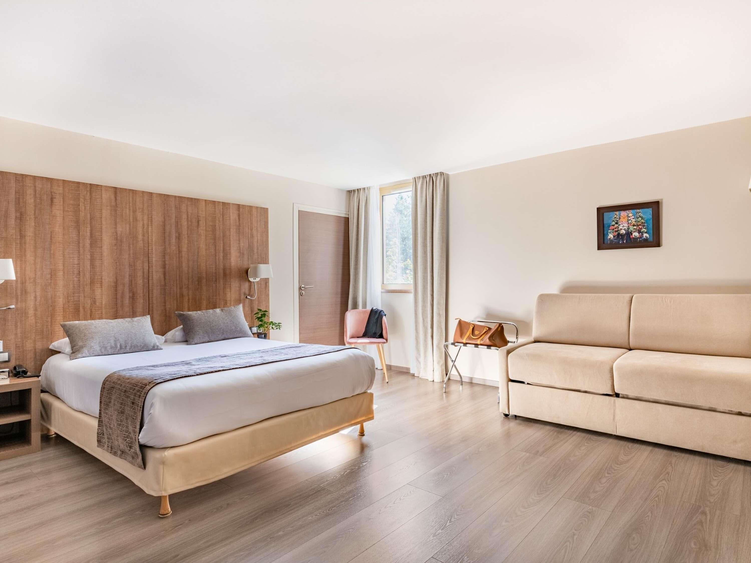 Una habitación de hotel moderna con una cama, un sofá, un escritorio y una silla.
