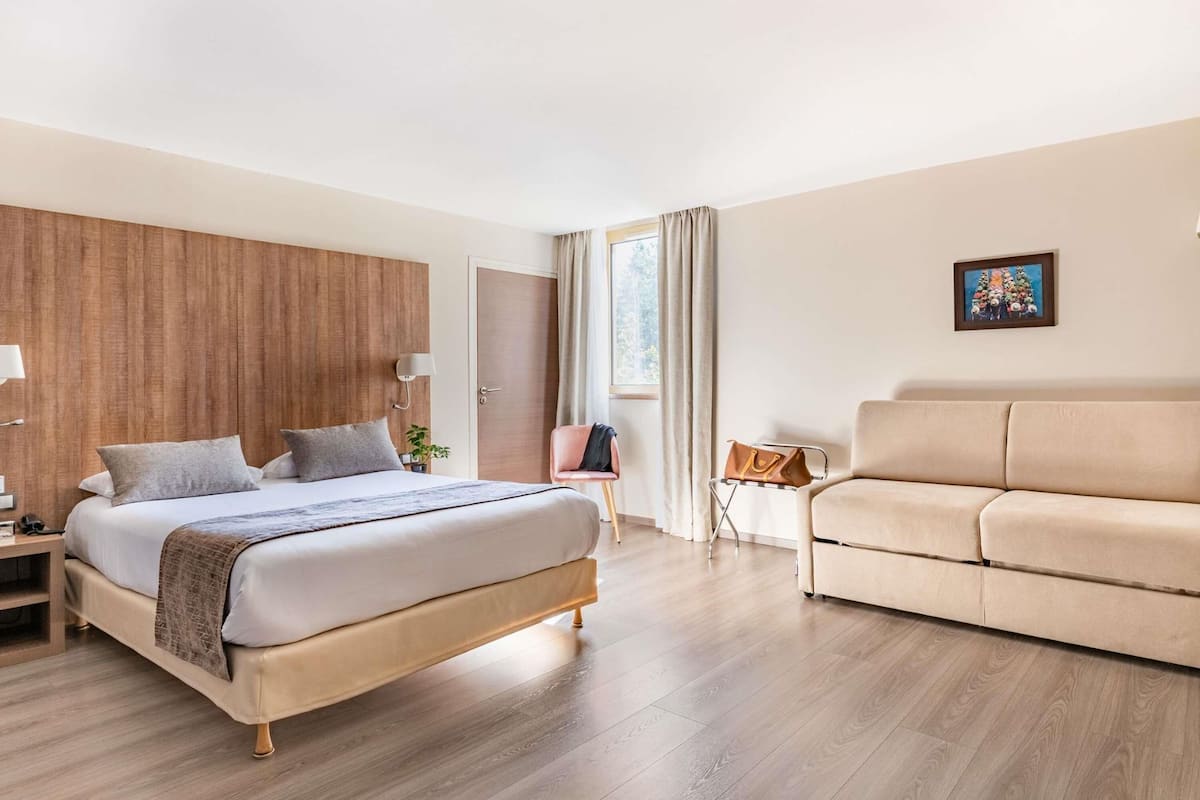 Une chambre d’hôtel moderne équipée d’un lit, d’un canapé, d’un bureau et d’une chaise.