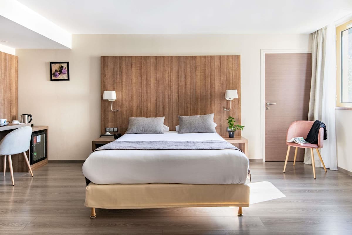 Une chambre d’hôtel moderne avec un grand lit, des tables de chevet, un bureau, une chaise et une porte.