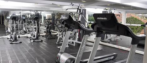Un gimnasio con cintas de correr, elípticas y máquinas de pesas.