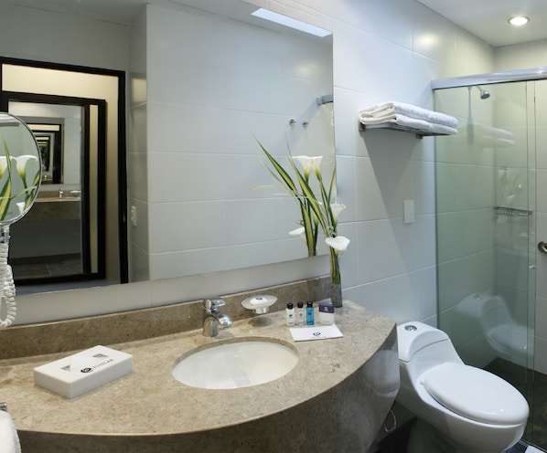 A modern bathroom with a round sink, a toilet, a glass shower enclosure, and a mirror with a reflection of the bathroom. - Estelar Recinto del Pensamiento Hotel (Manizales)