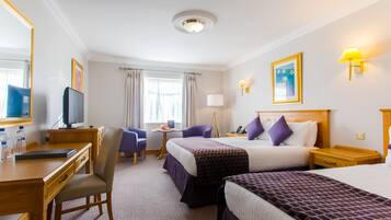 A hotel room with two beds, a desk, a chair, a television, and a window with curtains.