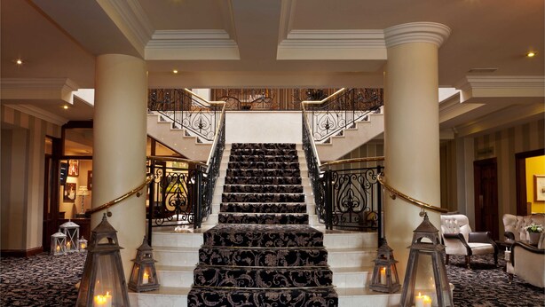 Una imponente escalera con barandillas ornamentadas y alfombra estampada, que conduce a un piso superior.