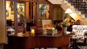 Un piano de cola en una habitación bien iluminada con un candelabro, un jarrón con flores y un letrero que indica que es un salón de bodas.