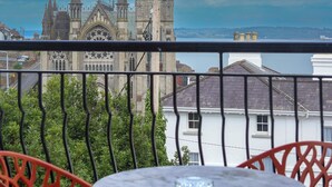 A balcony with a table and chairs overlooking a historic church with multiple spires.