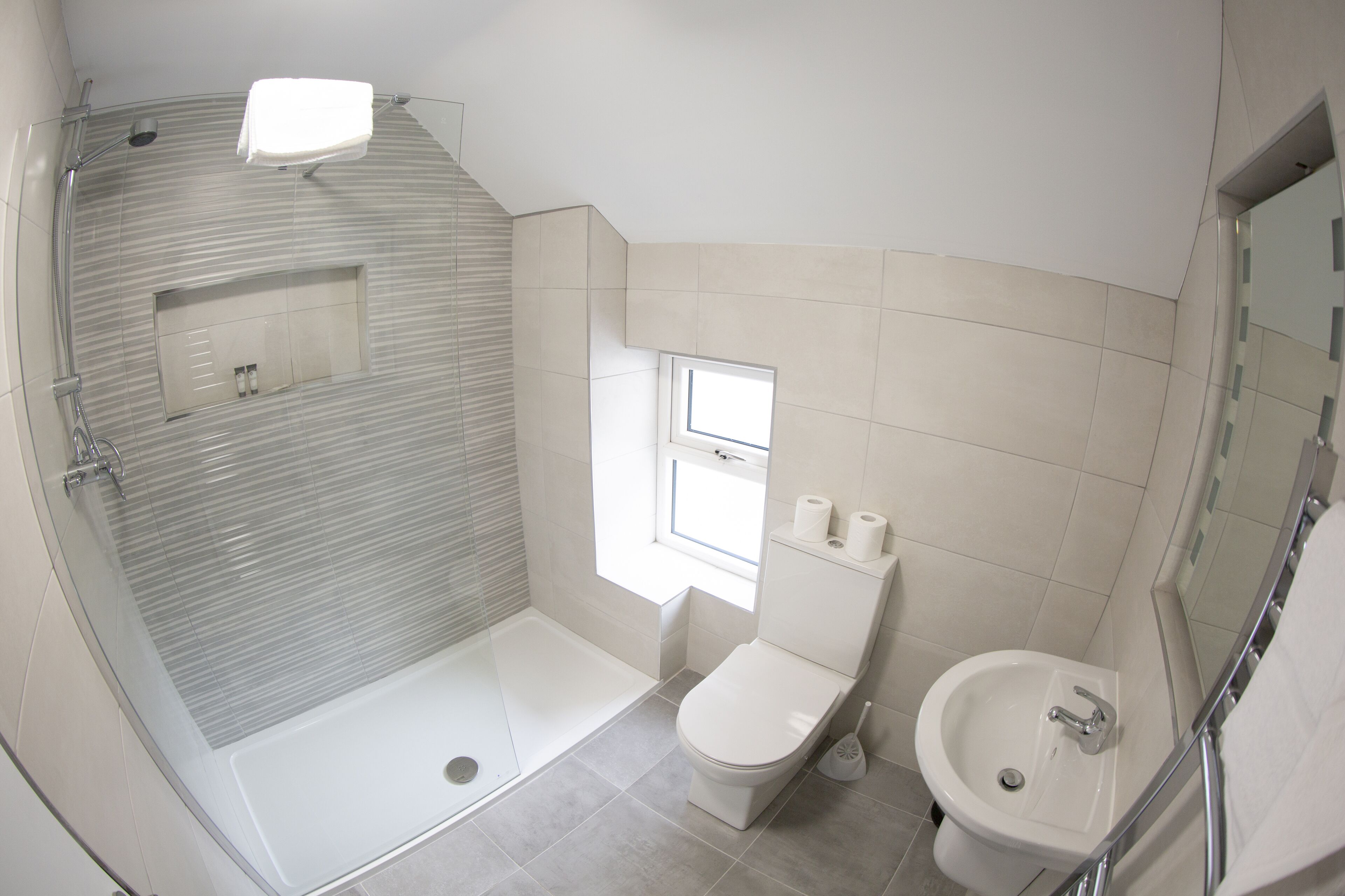 Un baño moderno con ducha de vidrio, inodoro y lavabo.