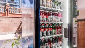 Un distributeur automatique de boissons, contenant une variété de produits, notamment des sodas et des jus de fruits, installé dans un endroit en plein air.