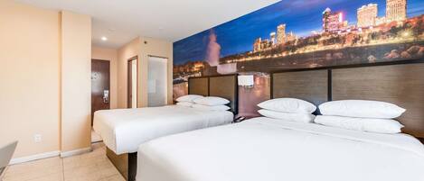 A hotel room with two beds, a cityscape mural on the wall, and a view of a waterfall.