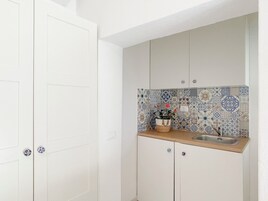 Una cocina compacta con armarios blancos, salpicadero de azulejos y encimera de madera.