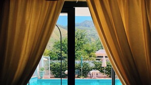 A view through a window with curtains, leading to a swimming pool and a staircase. - Hotel Lord Byron (Forio)