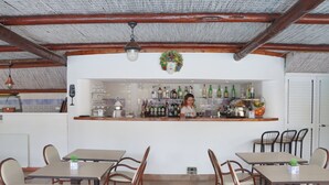 A restaurant with a bar area, wooden ceiling beams, and a variety of seating options including tables and chairs. - Hotel Lord Byron (Forio)