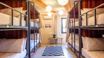 A dormitory room with bunk beds, a small table, and a chair.