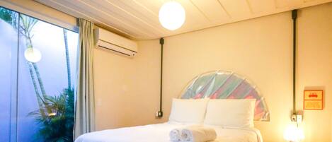 A hotel room with a bed, a nightstand, a lamp, and a window with curtains.