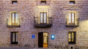 A stone building with three windows and a central balcony. There are signs indicating a hotel and a restaurant. - Hotel  YIT La Casona del Arco (Baeza)