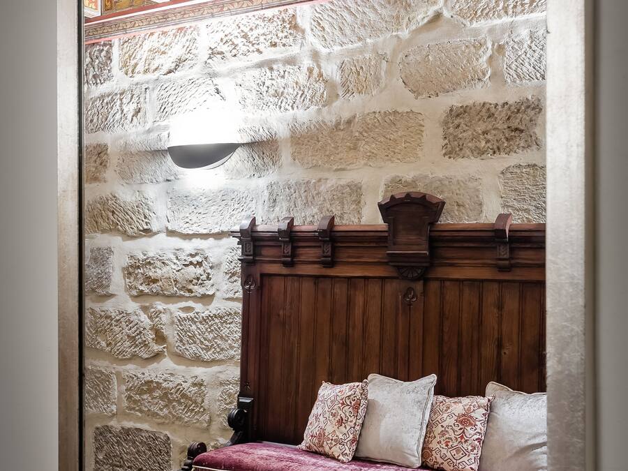 Una habitación con paredes de piedra, un banco de madera y un techo decorativo.