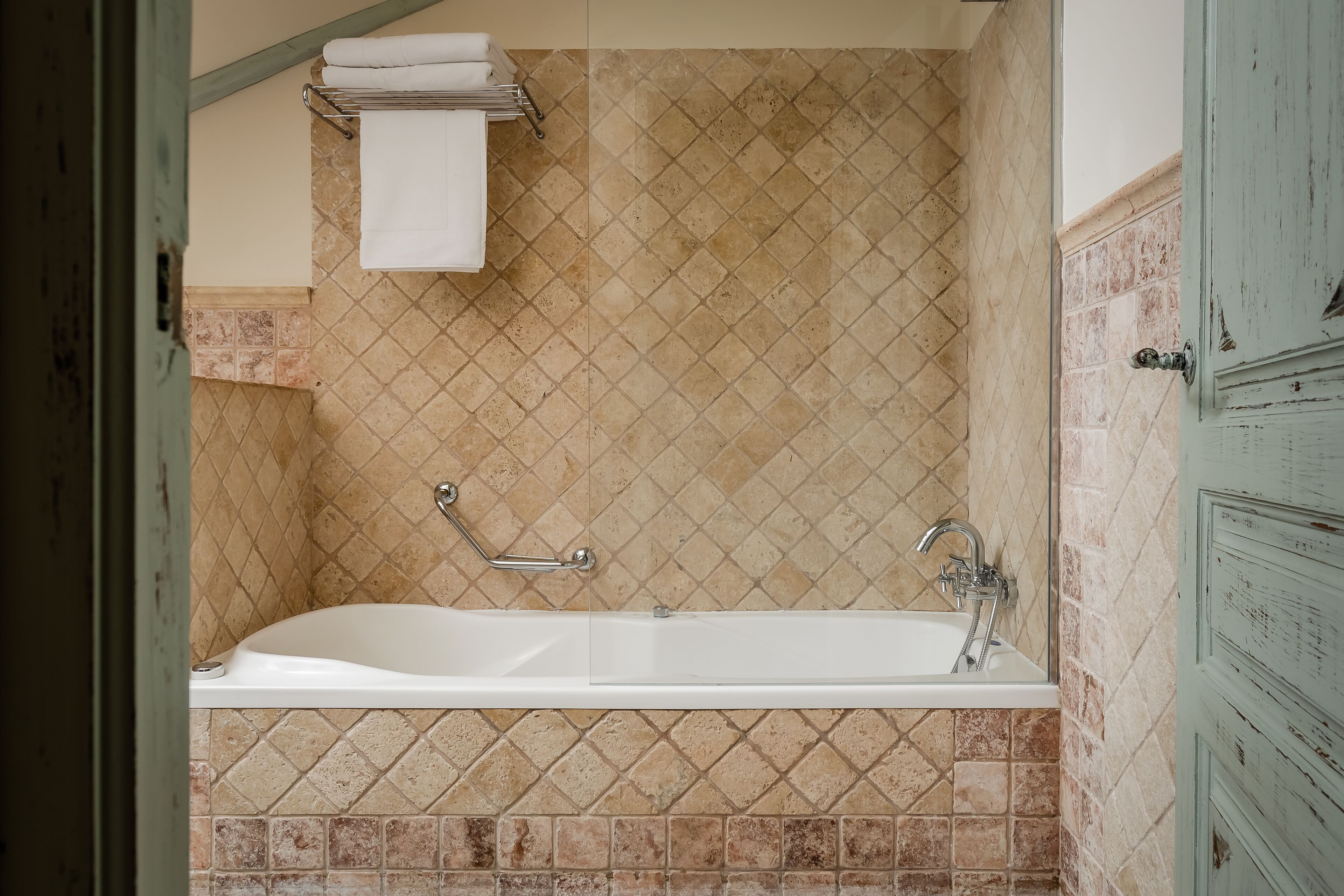 A bathroom with a bathtub, tiled walls, and a towel rack.