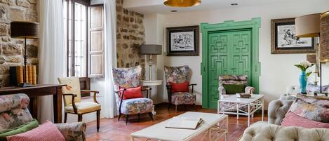 Uma sala de estar acolhedora com móveis estampados floralmente, uma porta verde e um chão ladrilhado.