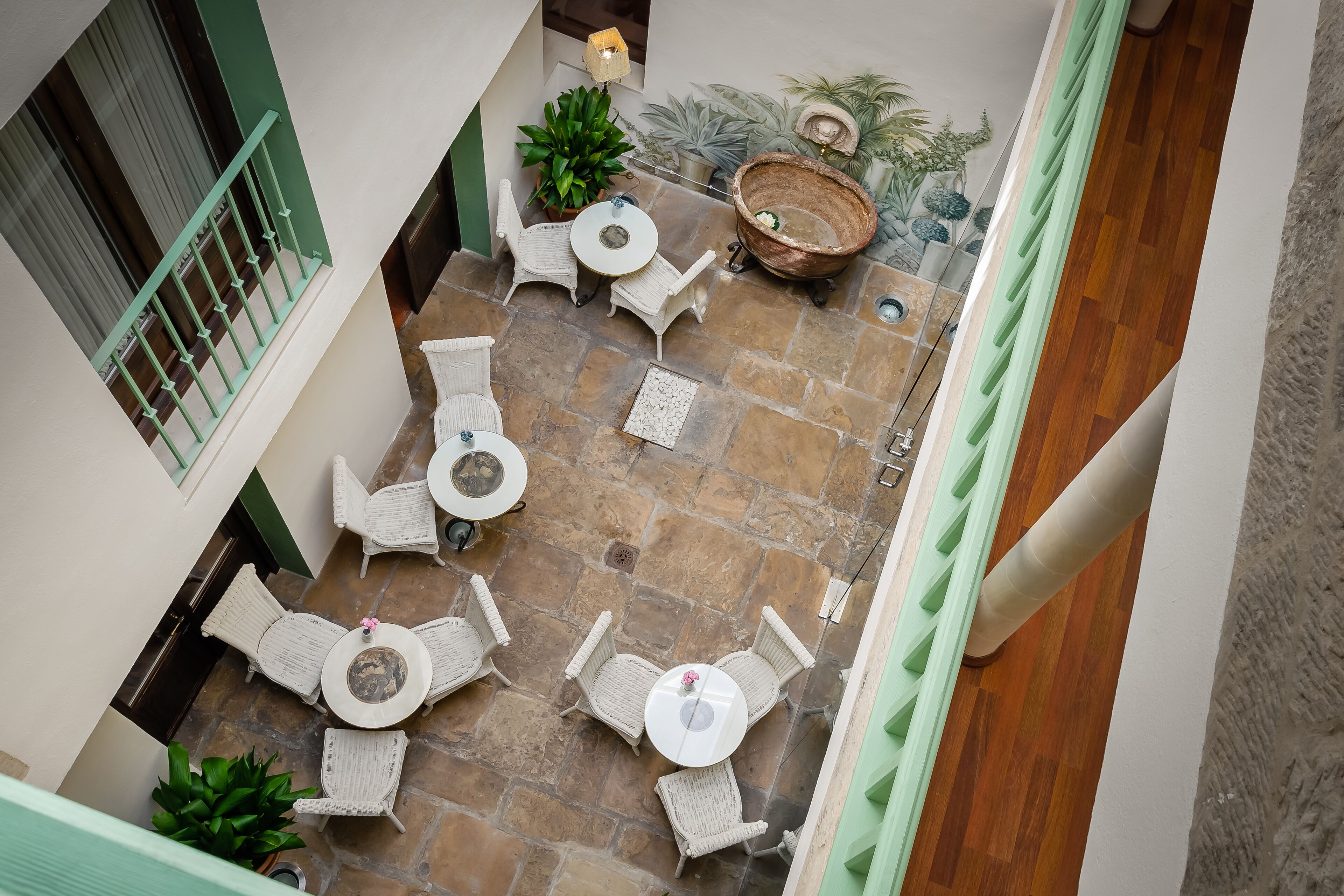 Un patio con suelo de piedra, mobiliario de mimbre y plantas en macetas.