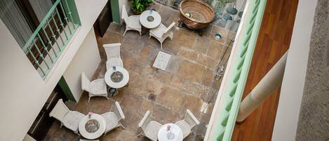 Un patio con suelo de piedra, mobiliario de mimbre y plantas en macetas.