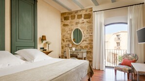A bedroom with a bed, a desk, a chair, and a balcony with a view of buildings. - Hotel  YIT La Casona del Arco (Baeza)