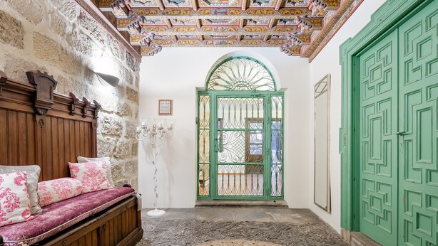 A room with a wooden bench, a green door, and a patterned floor. - Hotel  YIT La Casona del Arco (Baeza)