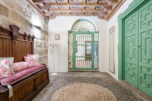 A room with a wooden bench, a green door, and a patterned floor. - Hotel  YIT La Casona del Arco (Baeza)