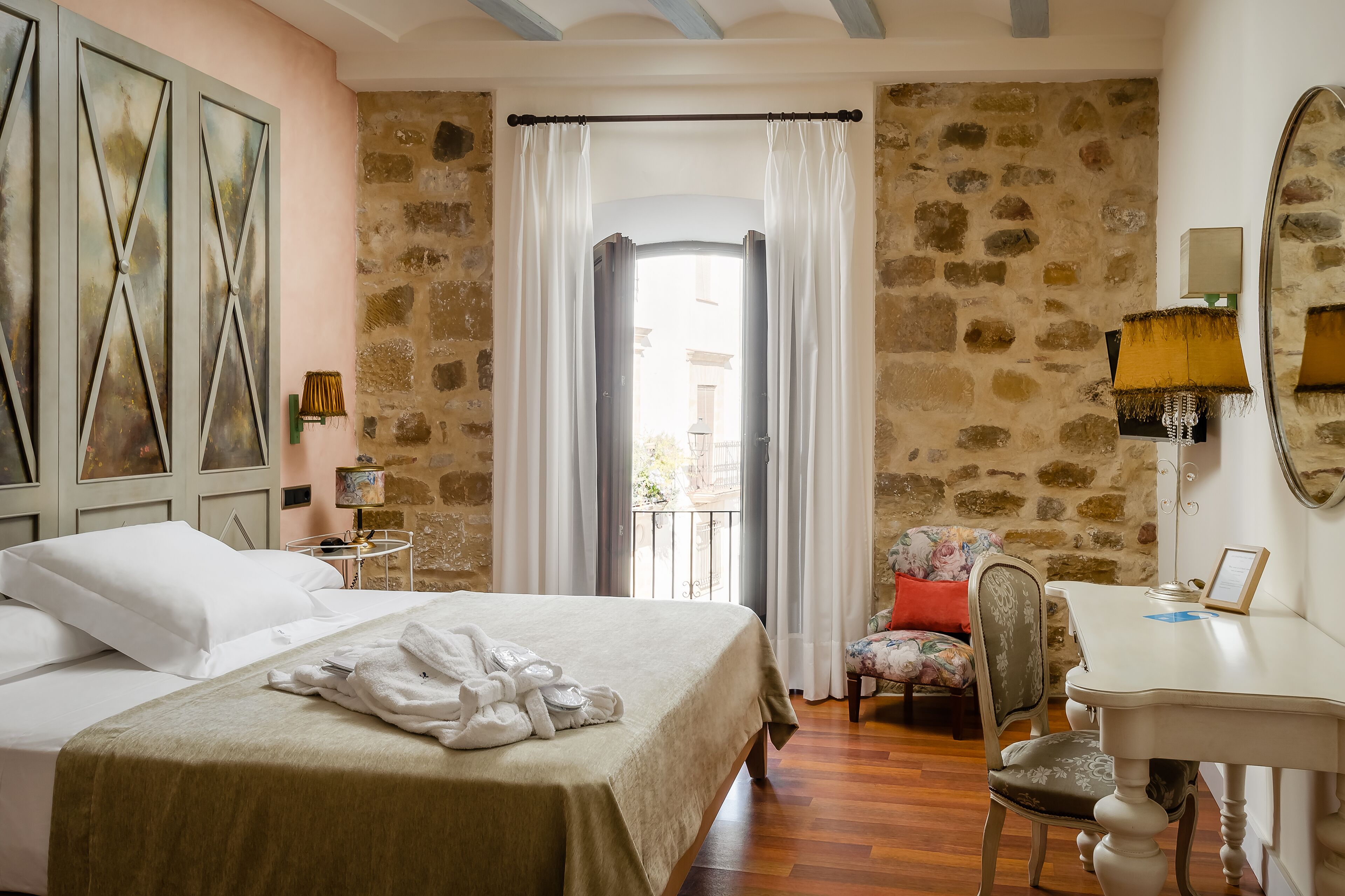 Un dormitorio con cama, una silla, un escritorio y vistas al exterior.