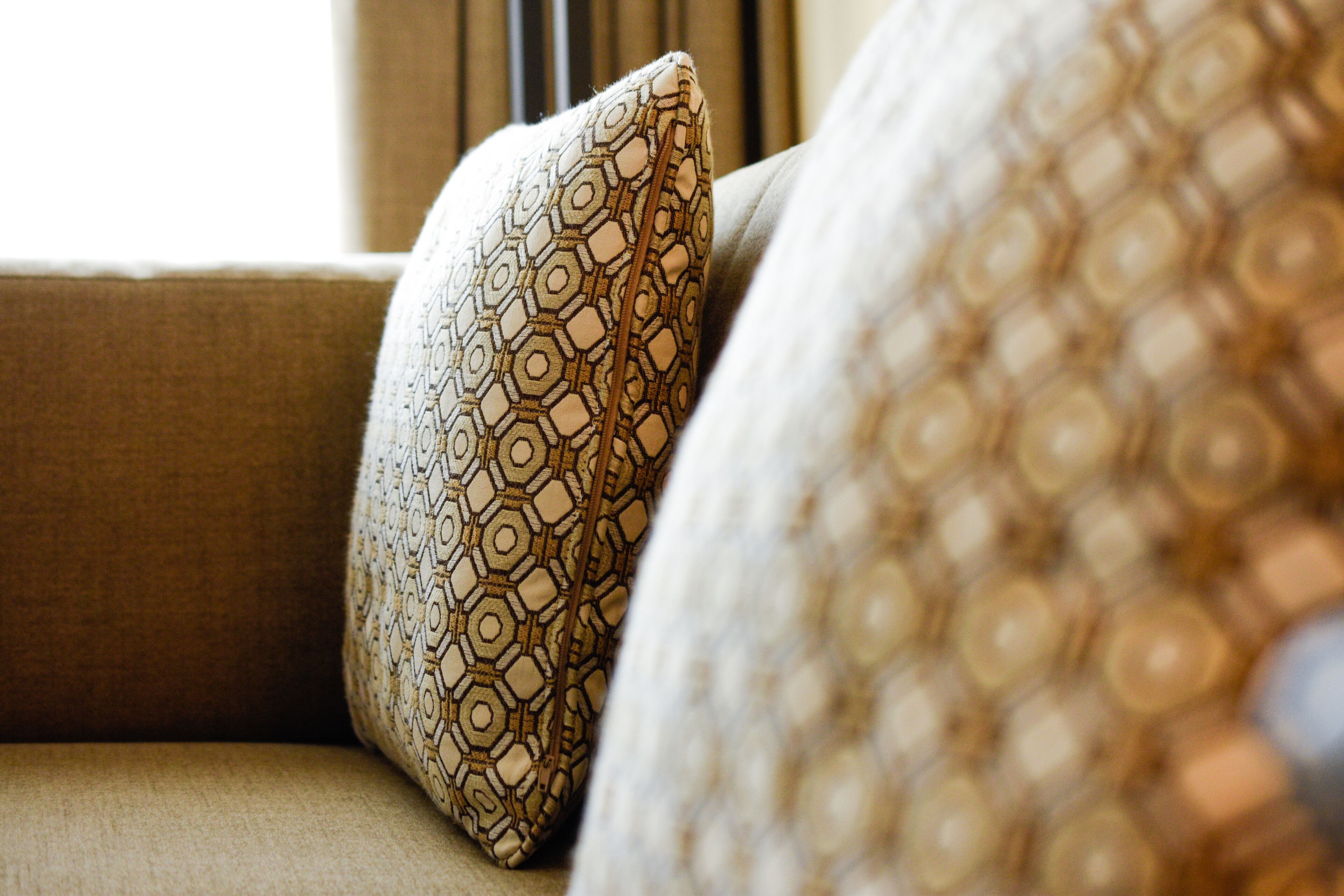 A close-up of a patterned pillow on a beige sofa.
