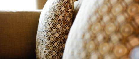 A close-up of a patterned pillow on a beige sofa.