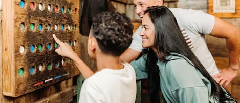 Ein Holzbrett mit mehreren Löchern, vermutlich ein Spiel- oder Aktivitätsbrett, in rustikaler Umgebung mit Holzwänden und einem gerahmten Bild an der Wand.