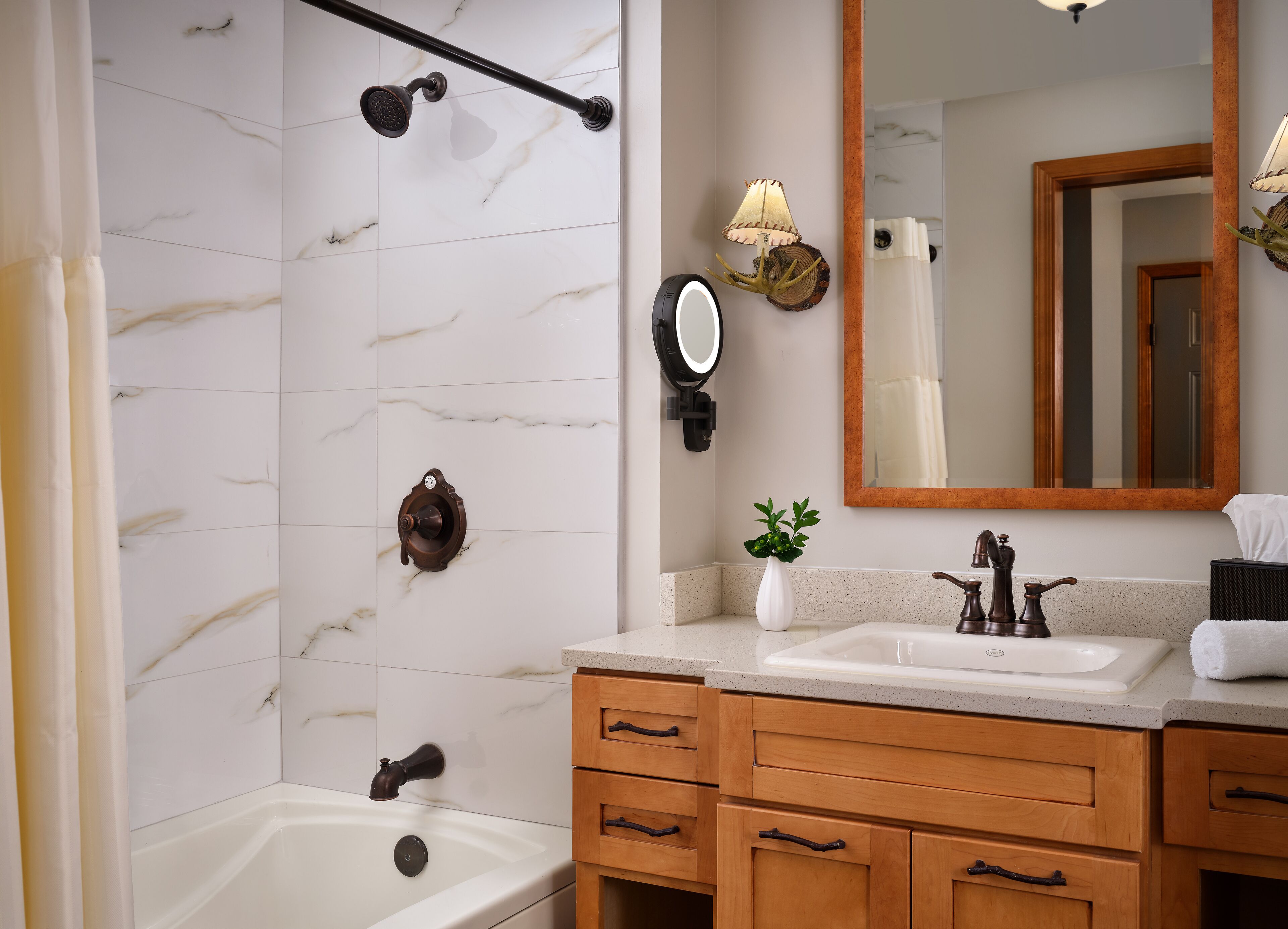 A bathroom with a bathtub, a sink with a mirror, wooden cabinets, and a towel rack.