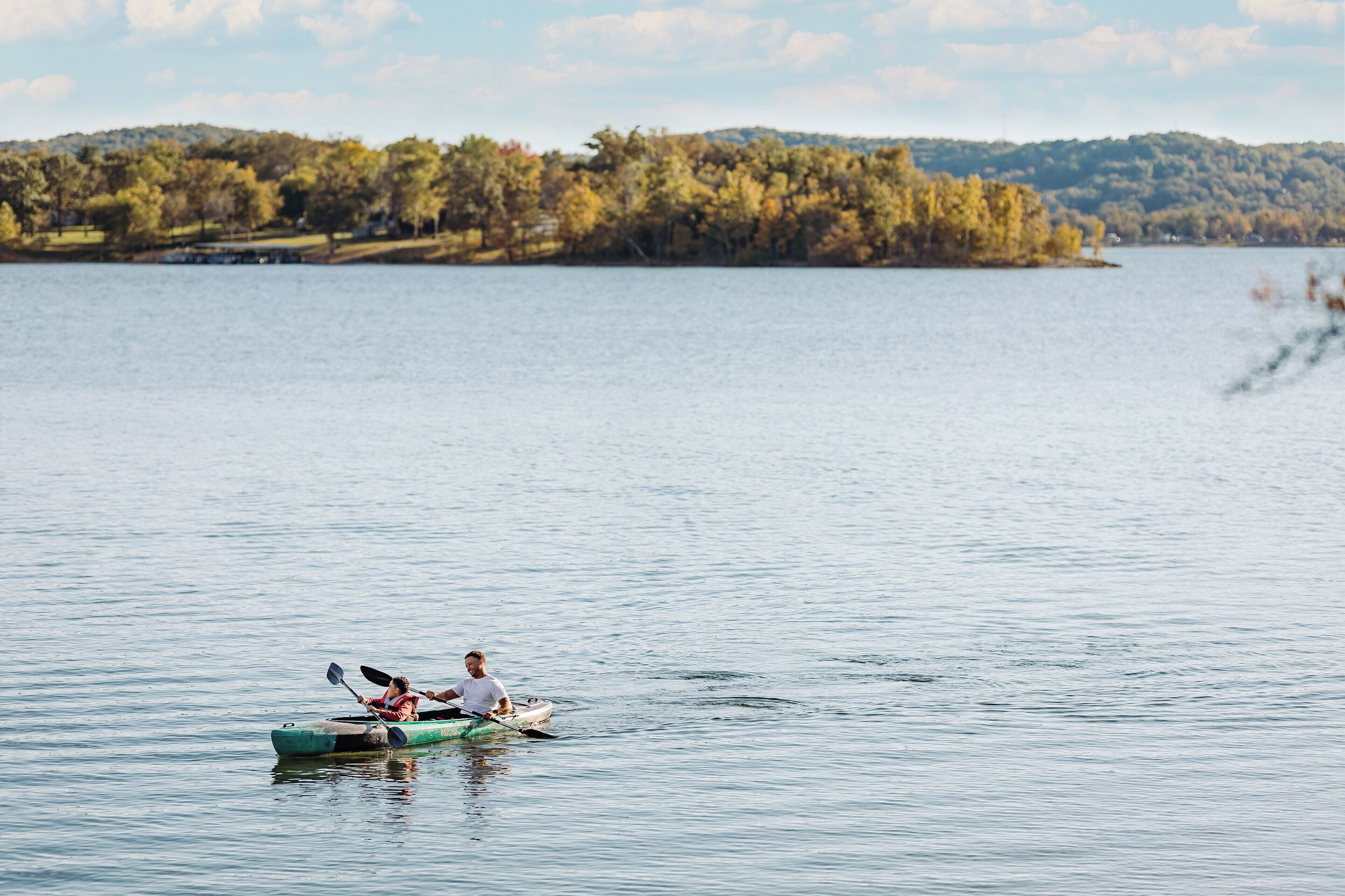 A calm lake with kayaks and a person paddling.