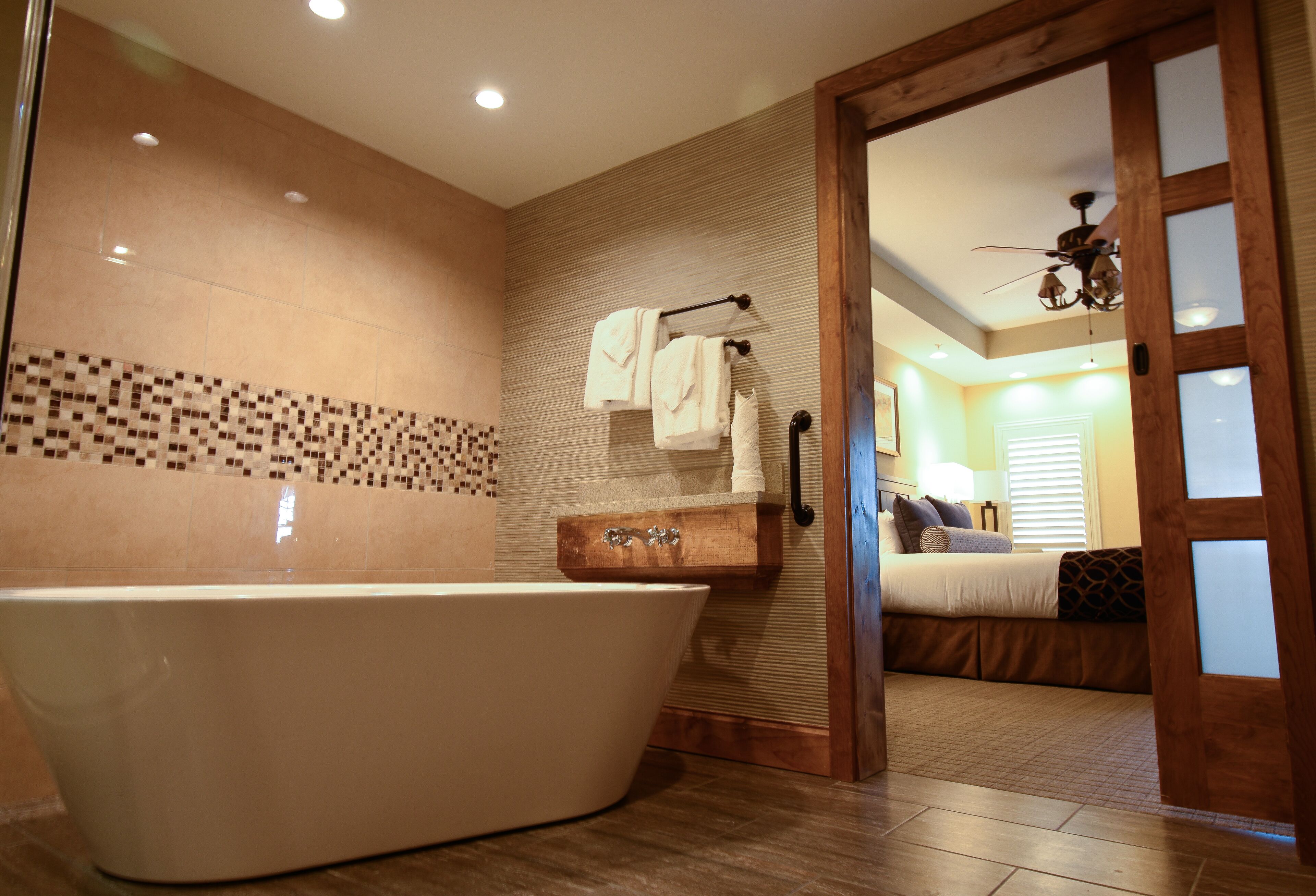 Une salle de bain moderne avec une baignoire sur pieds, un meuble-lavabo en bois avec un miroir et un porte-serviettes.