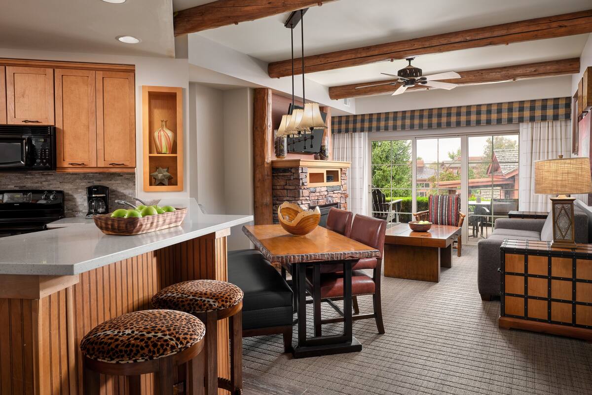 Una cocina moderna con armarios de madera, una isla grande y una zona de comedor con mesa y sillas.