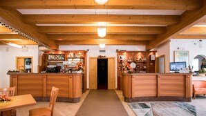 Un intérieur en bois avec un bar central, une table à manger entourée de chaises et un tapis à motifs sur le sol.