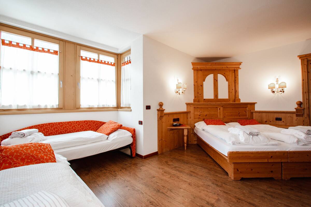 A room with two wooden beds, a wooden cabinet, and a window with curtains.