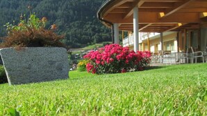 Une pelouse bien entretenue, agrémentée d’un jardinière en pierre et de fleurs roses éclatantes.