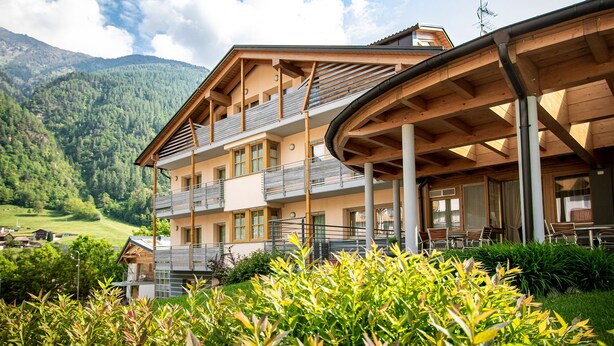 Un immeuble à plusieurs étages doté de balcons, d’un espace extérieur couvert et surplombant un paysage montagneux.