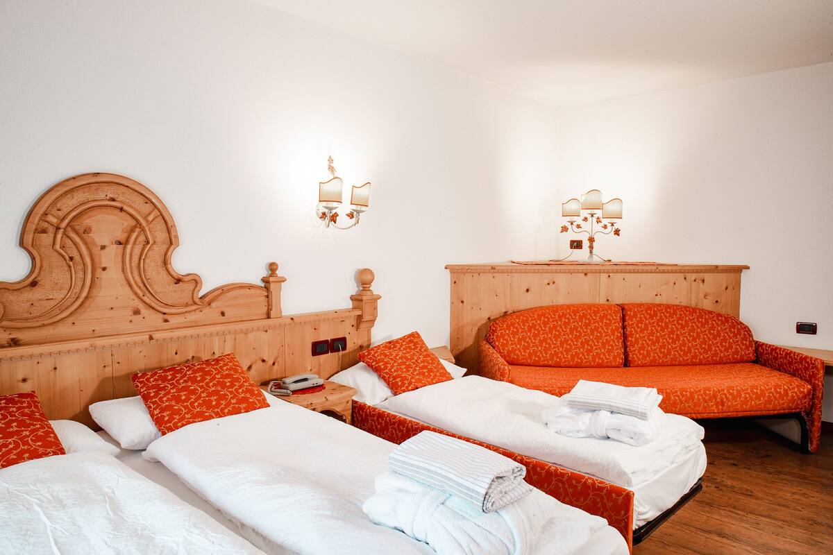 A hotel room with two beds, each with orange and white bedding, a wooden headboard, and a nightstand with a lamp.